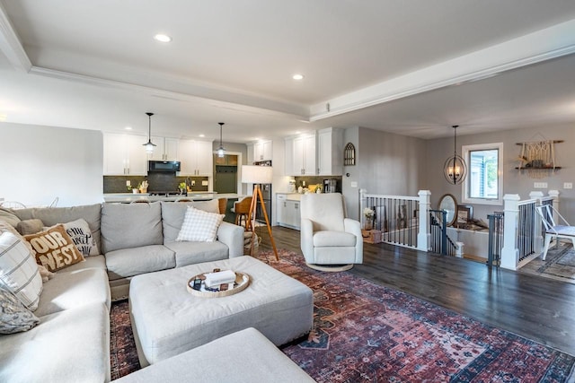 living room featuring an inviting chandelier, a tray ceiling, and dark hardwood / wood-style flooring