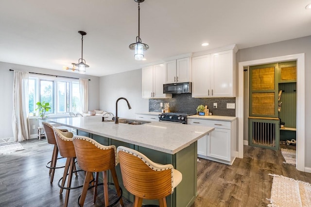 kitchen with black appliances, a center island with sink, sink, and white cabinets