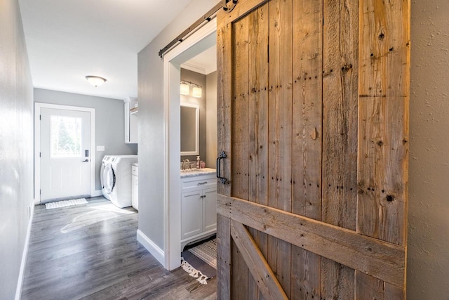 corridor featuring a barn door, dark hardwood / wood-style floors, independent washer and dryer, and sink