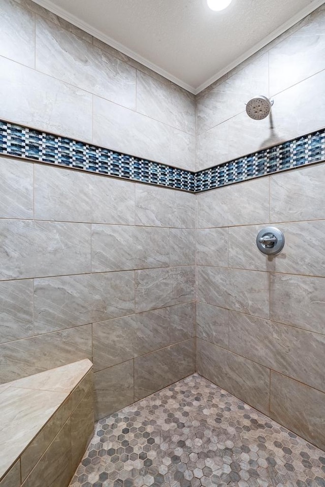 bathroom with ornamental molding and tiled shower