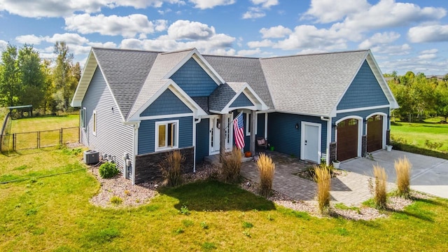 view of front of house with cooling unit, a garage, and a front yard