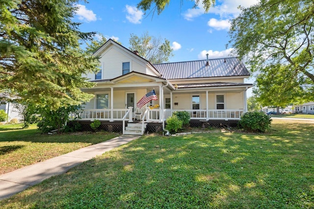view of front facade featuring covered porch, a front yard, and metal roof
