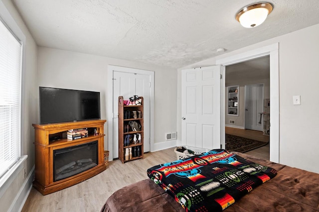 bedroom featuring a textured ceiling, light hardwood / wood-style floors, and multiple windows