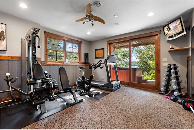 workout area featuring a textured ceiling, wooden walls, and ceiling fan