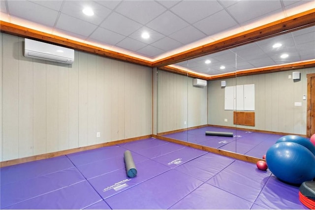 interior space with an AC wall unit, wood walls, and a drop ceiling