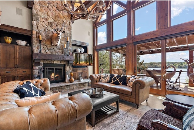 living room featuring a notable chandelier, a high ceiling, light hardwood / wood-style floors, and a fireplace