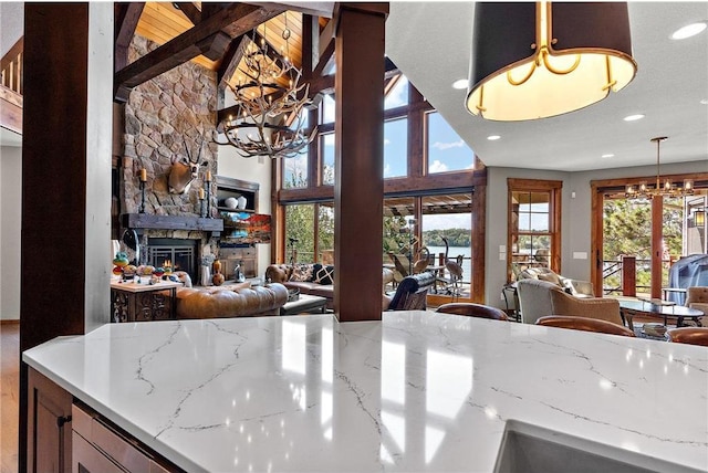 kitchen with light stone countertops, a fireplace, pendant lighting, and plenty of natural light