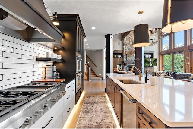 kitchen featuring pendant lighting, white cabinetry, custom range hood, light hardwood / wood-style flooring, and appliances with stainless steel finishes