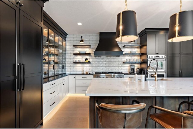 kitchen with light hardwood / wood-style flooring, pendant lighting, a breakfast bar, and white cabinets