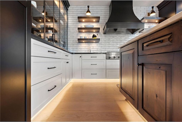 kitchen with decorative backsplash, light hardwood / wood-style floors, range hood, and white cabinets