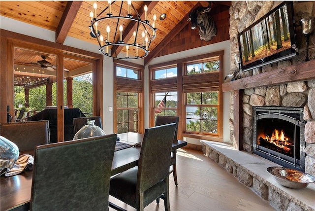 dining room with light wood-type flooring, a stone fireplace, high vaulted ceiling, wooden ceiling, and ceiling fan with notable chandelier