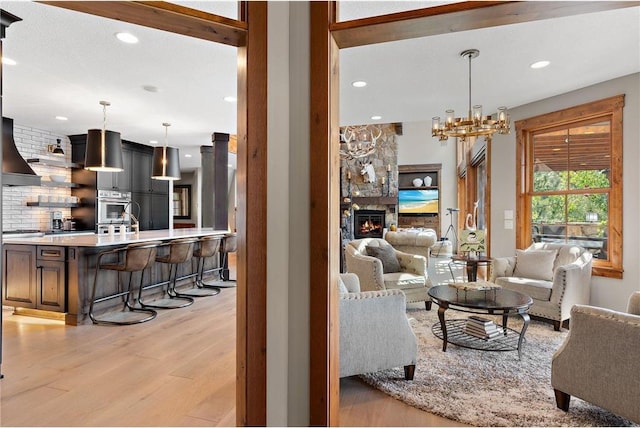 living room with light wood-type flooring, a fireplace, and an inviting chandelier