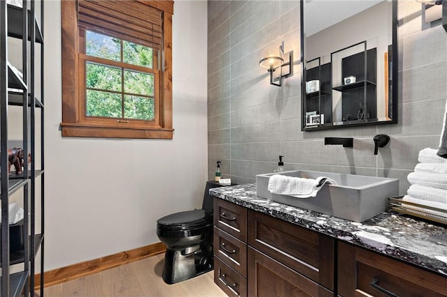 bathroom with vanity, wood-type flooring, backsplash, tile walls, and toilet