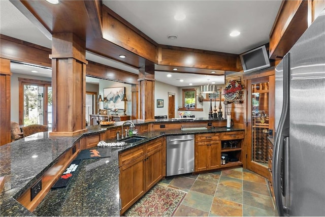 bar featuring dark stone countertops, sink, appliances with stainless steel finishes, and decorative columns