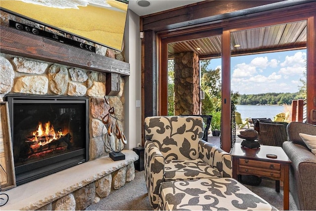 carpeted living room featuring a water view and a stone fireplace