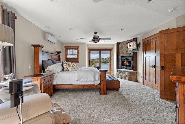 bedroom with ceiling fan, access to outside, a stone fireplace, light carpet, and an AC wall unit