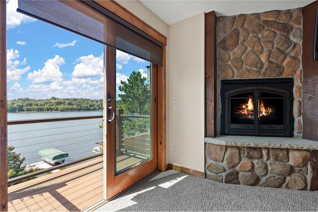 doorway featuring carpet floors, a stone fireplace, and a water view