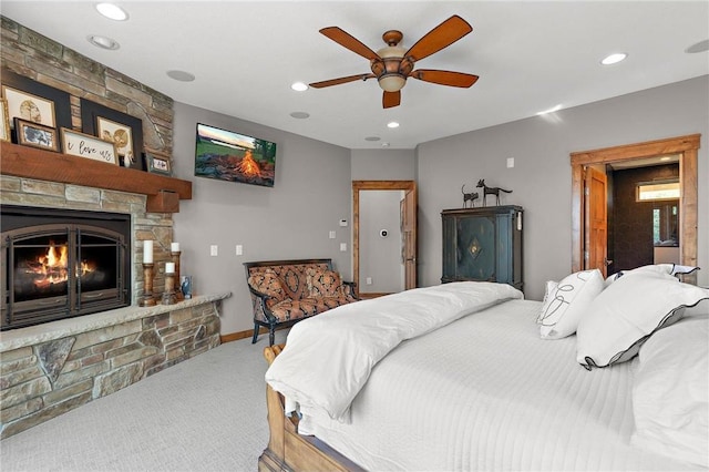 bedroom featuring ceiling fan, carpet flooring, and a stone fireplace