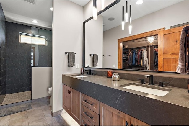 bathroom featuring tiled shower, vanity, toilet, and tile patterned floors