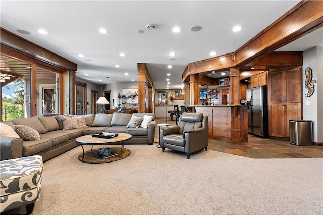 living room with a textured ceiling, carpet flooring, and indoor bar