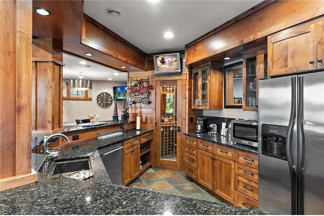 kitchen featuring dark stone countertops, pendant lighting, stainless steel appliances, and sink