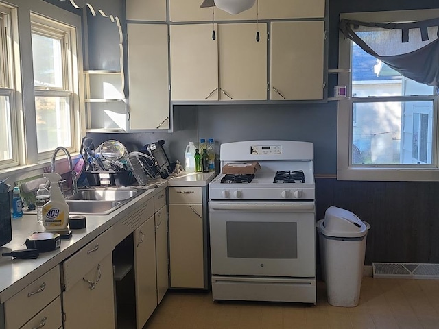 kitchen featuring white cabinetry, white range with gas cooktop, and sink