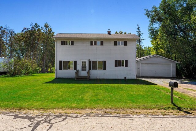 view of front of home featuring a garage, a front lawn, and an outbuilding