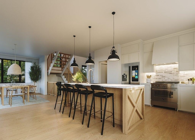 kitchen with an island with sink, stainless steel appliances, light wood-type flooring, and white cabinetry