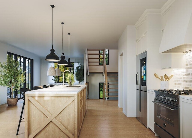 kitchen with light hardwood / wood-style floors, high end range, a center island with sink, custom exhaust hood, and stainless steel fridge with ice dispenser