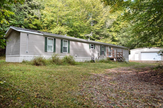 manufactured / mobile home featuring an outdoor structure, a garage, and a front lawn