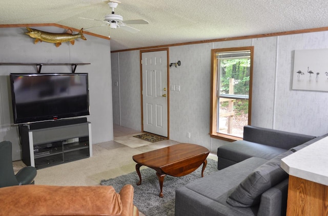 living room featuring a textured ceiling, lofted ceiling, carpet floors, ornamental molding, and ceiling fan