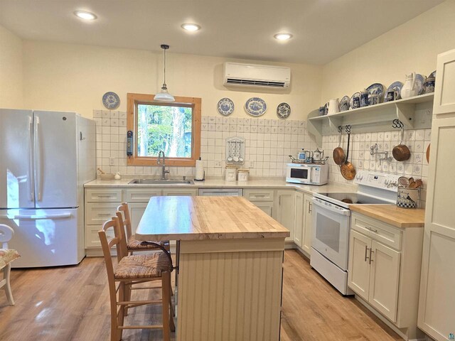 kitchen with white appliances, a kitchen island, butcher block countertops, a wall unit AC, and sink