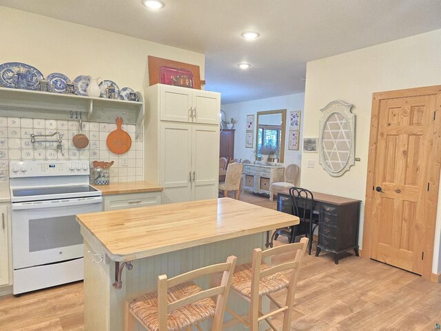 kitchen featuring wooden counters, white cabinetry, white electric range, a breakfast bar area, and light wood-type flooring