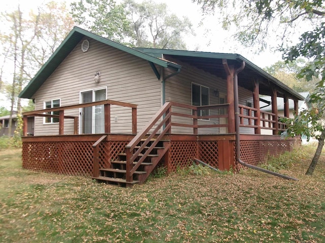 rear view of house featuring a deck and a yard