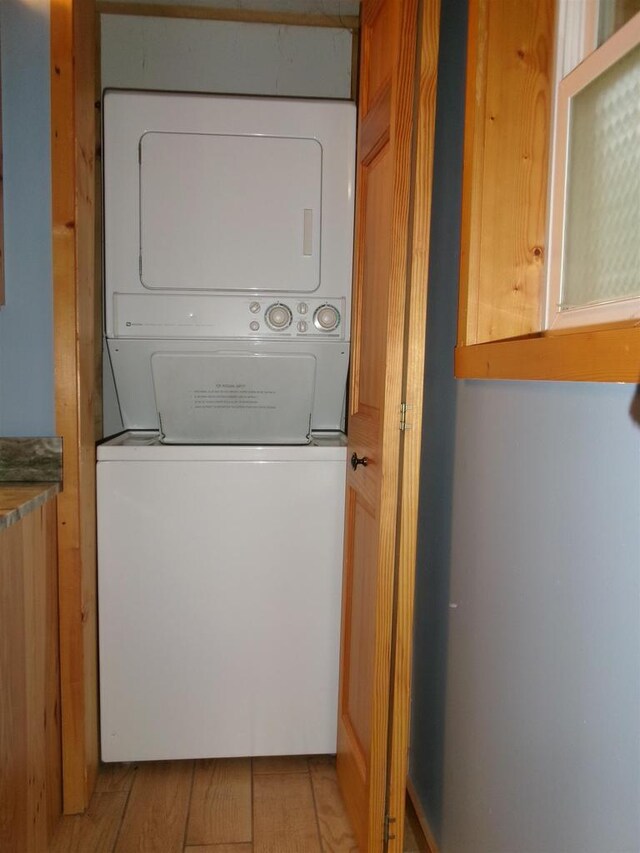 clothes washing area with stacked washing maching and dryer