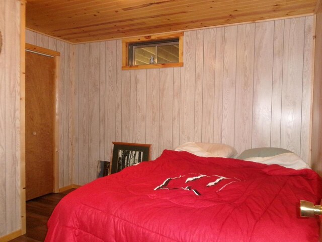 bedroom with wood walls, dark hardwood / wood-style floors, and wooden ceiling