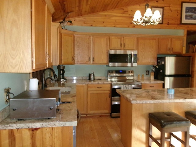 kitchen with lofted ceiling, sink, light hardwood / wood-style flooring, appliances with stainless steel finishes, and a notable chandelier