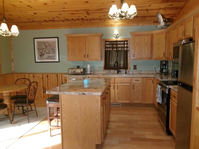 kitchen featuring pendant lighting, a chandelier, appliances with stainless steel finishes, a center island, and light hardwood / wood-style floors