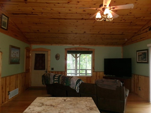 living room with hardwood / wood-style flooring, vaulted ceiling, wood walls, ceiling fan, and wooden ceiling