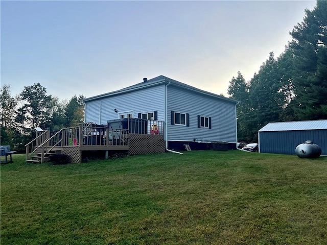 back house at dusk with a storage shed, a deck, and a yard