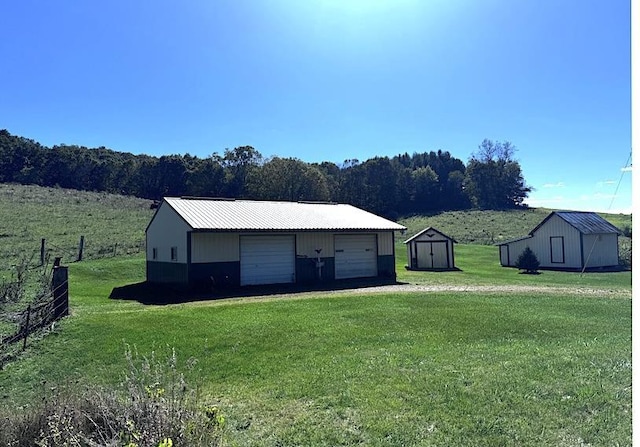 view of front facade with a front yard, a rural view, and a storage shed