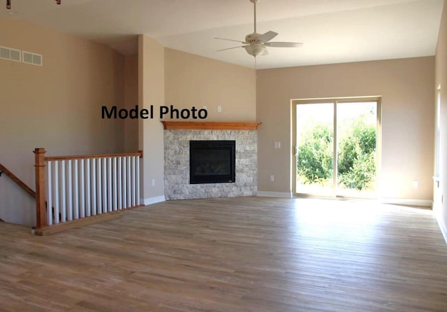 unfurnished living room with a stone fireplace, hardwood / wood-style floors, and ceiling fan