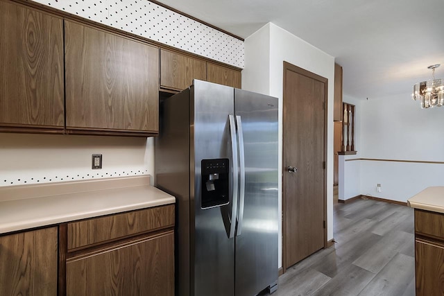 kitchen with hanging light fixtures, a notable chandelier, hardwood / wood-style flooring, and stainless steel fridge