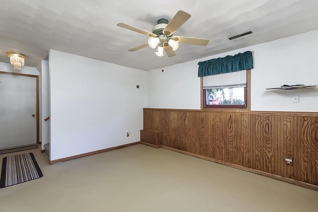 carpeted empty room featuring wooden walls and ceiling fan