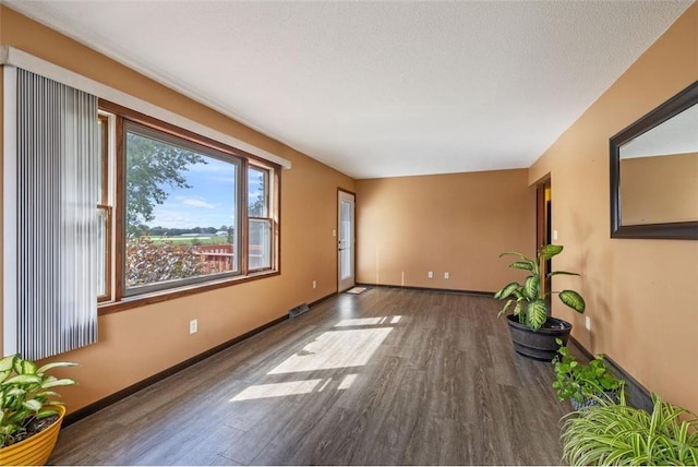 empty room featuring a textured ceiling and dark wood-type flooring