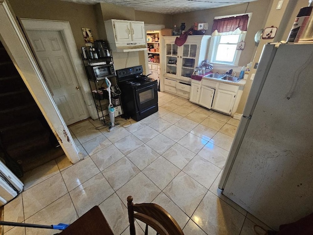 kitchen with white cabinets, light tile patterned floors, white fridge, a textured ceiling, and black range with electric cooktop