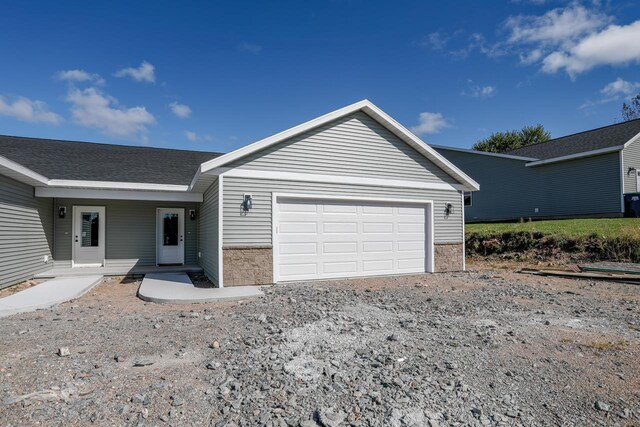 ranch-style home featuring a shingled roof and an attached garage