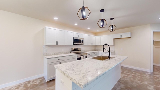 kitchen featuring pendant lighting, stainless steel appliances, an island with sink, and white cabinets