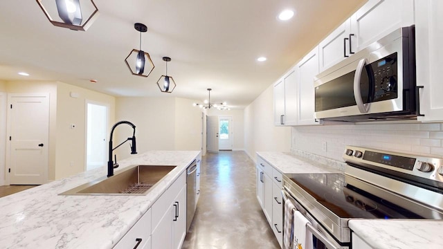 kitchen with tasteful backsplash, hanging light fixtures, appliances with stainless steel finishes, white cabinets, and a sink