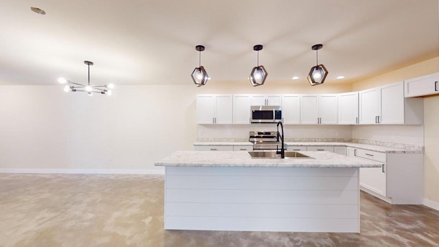 kitchen featuring a kitchen island with sink, white cabinetry, stainless steel appliances, and decorative light fixtures